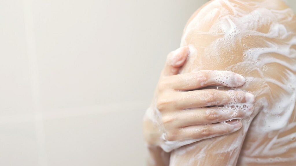 Femme qui se lave l'épaule avec la mousse d'un savon au lait d'ânesse - La Savonnerie de Nyons